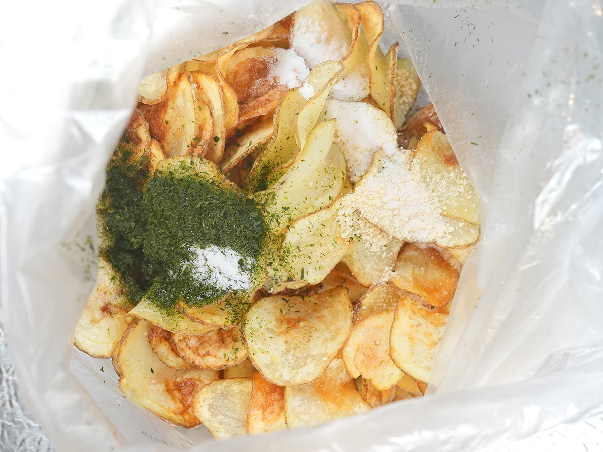 ポリ袋に揚げたじゃがいもとAの青のり、鶏がらスープの素、塩を入れるシーン