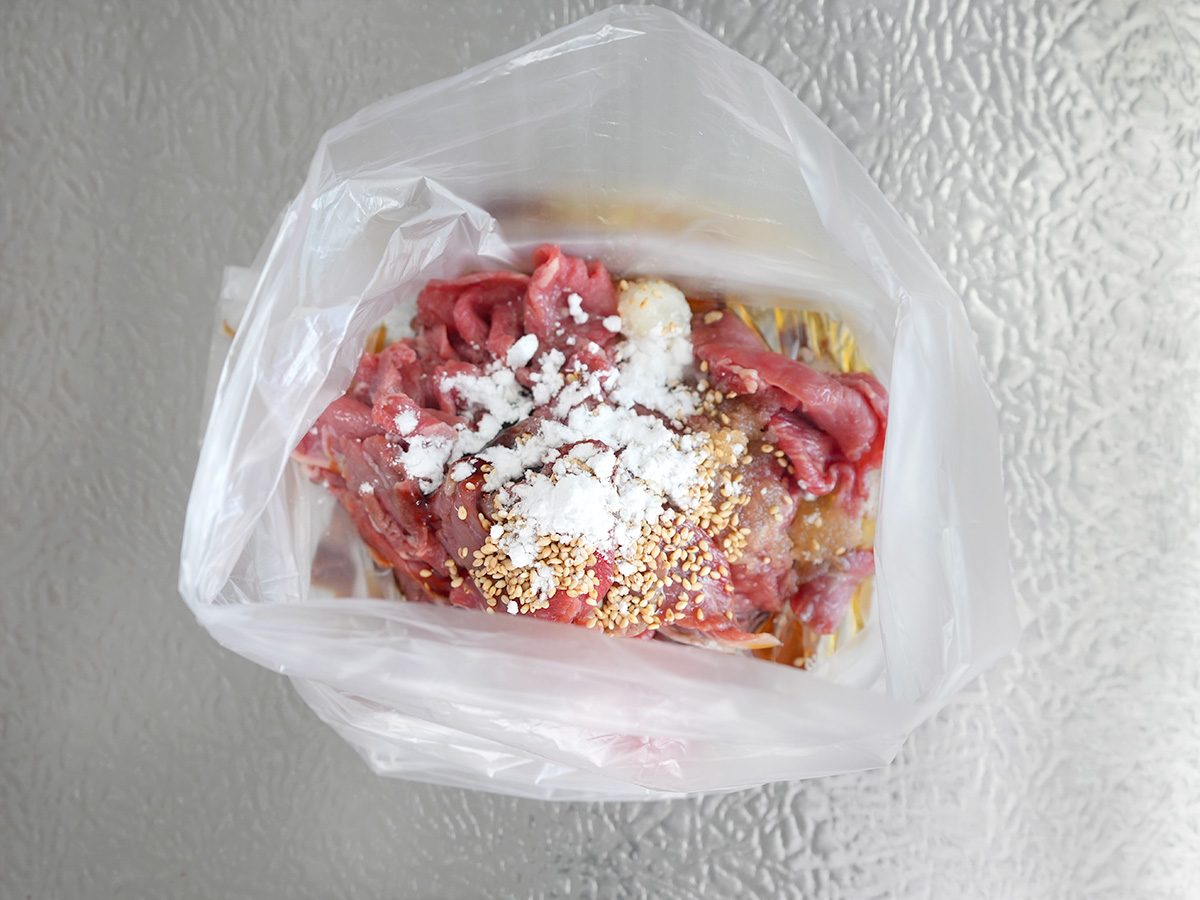 ポリ袋に牛肉とAのしょうゆ、砂糖、コチュジャン、白ごま、おろしにんにく、片栗粉を入れるシーン