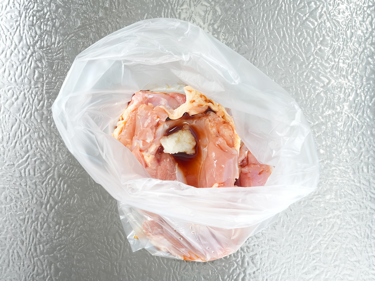 ポリ袋に鶏肉2枚とAの酒、しょうゆ、にんにくを加えるシーン