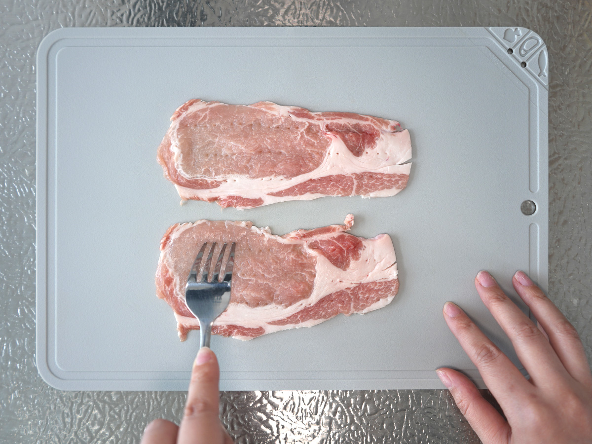 豚肉にフォークで穴をあけるシーン