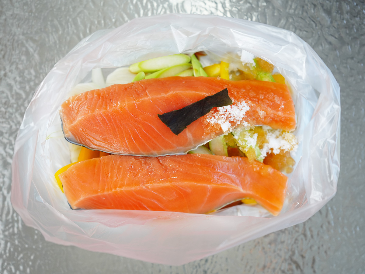 ポリ袋に玉ねぎ、パプリカ、アスパラガス、鮭、ポン酢、砂糖、昆布を入れたシーン