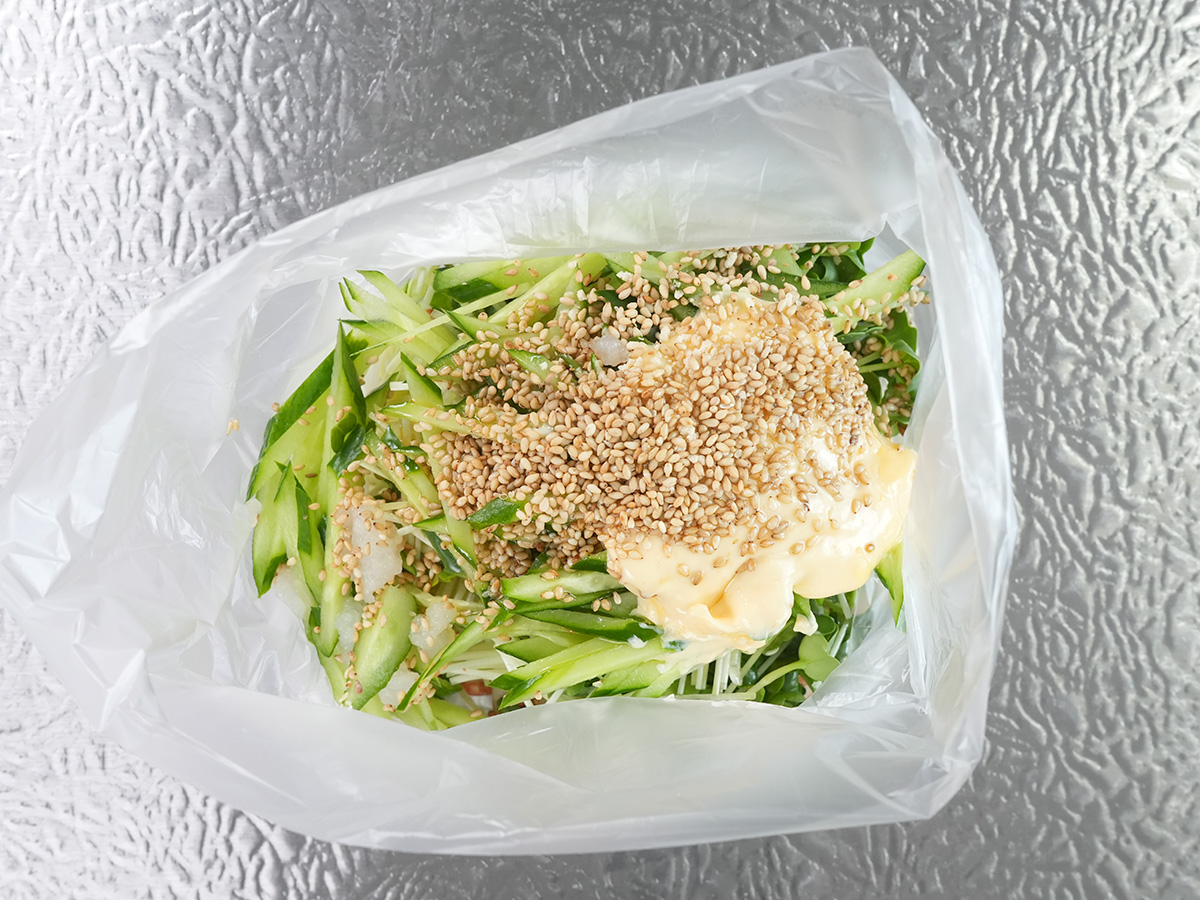 ポリ袋にちくわ、かいわれ、きゅうりとAのマヨネーズ、鶏がらスープの素、いりごま、にんにく、ごま油を入れるシーン