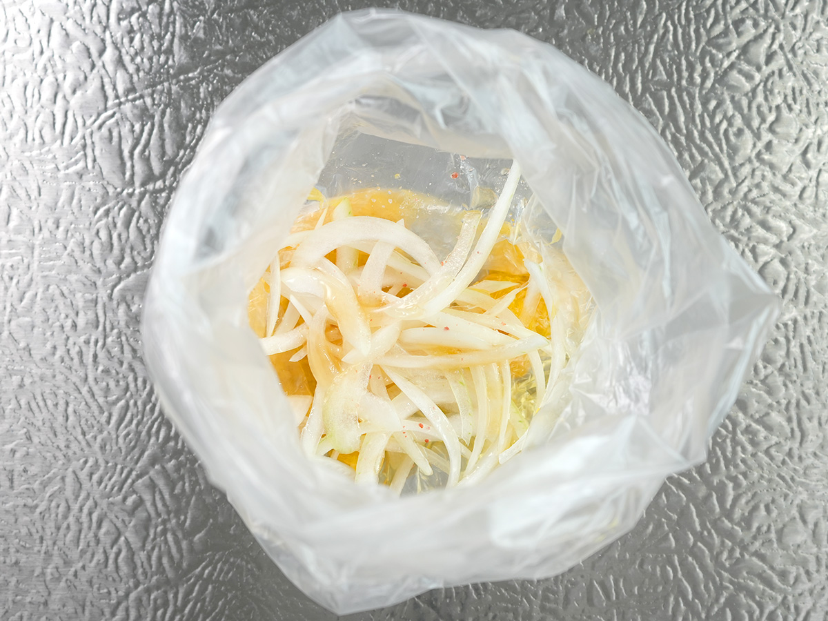 ポリ袋に玉ねぎとAのオリーブオイル、はちみつ、塩を加えるシーン