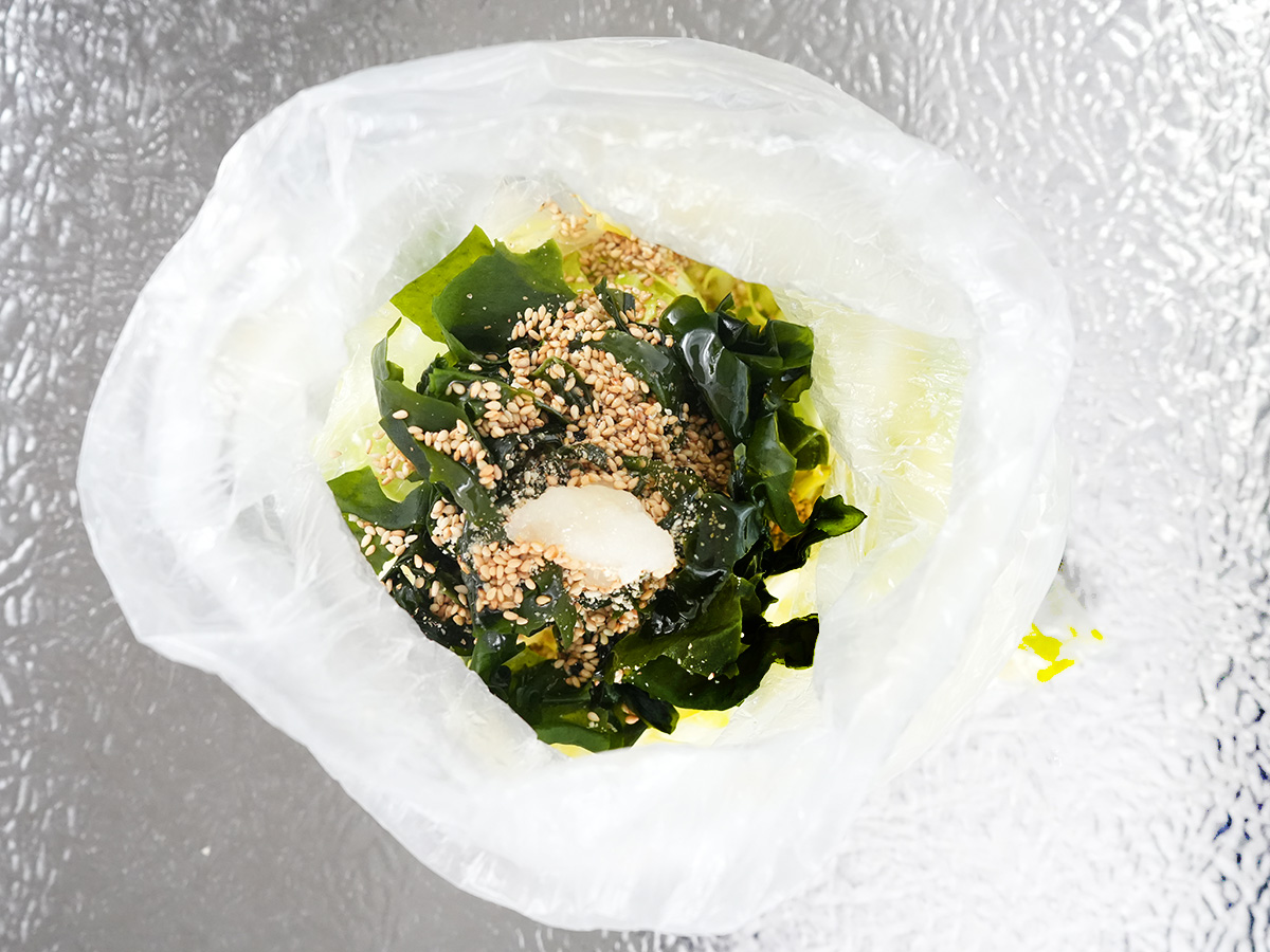 ポリ袋にわかめとキャベツ、Aのいりごま、ごま油、にんにく、鶏がらスープの素を入れてよく混ぜるシーン