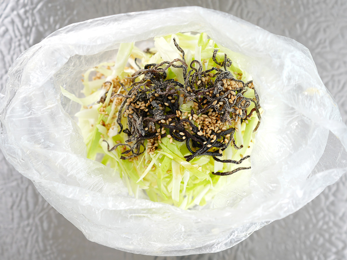 切り干し大根が入ったポリ袋にキャベツとAの塩昆布、お酢、ごま油、白いりごまを加えるシーン